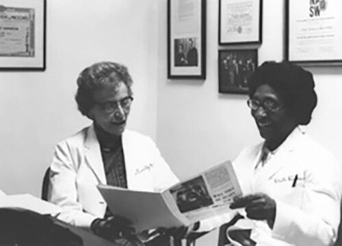 Helen O. Dickens in white coat conferring with another female doctor in an office