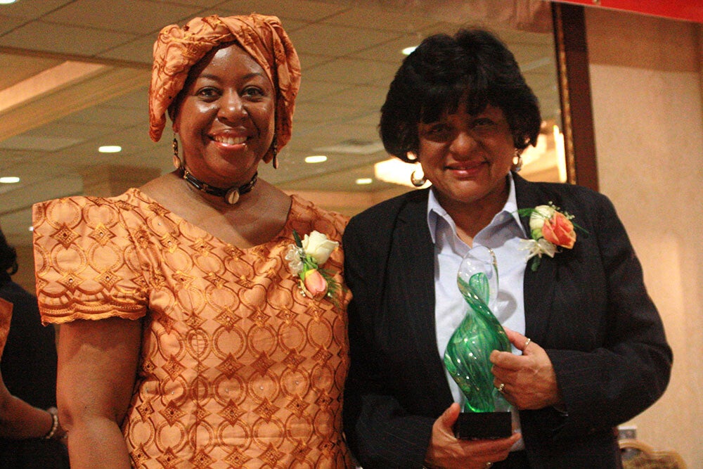 an award recipient holding a green glass  award next to another attendee