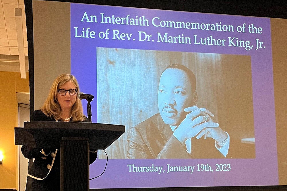 President Liz Magill speaking at a ceremony in front of photo of MLK