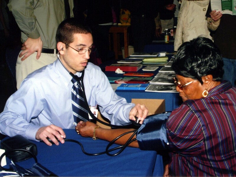 young volunteer taking a blood pressure reading for an older person
