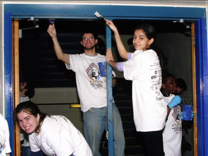 three student volunteers painting a doorway