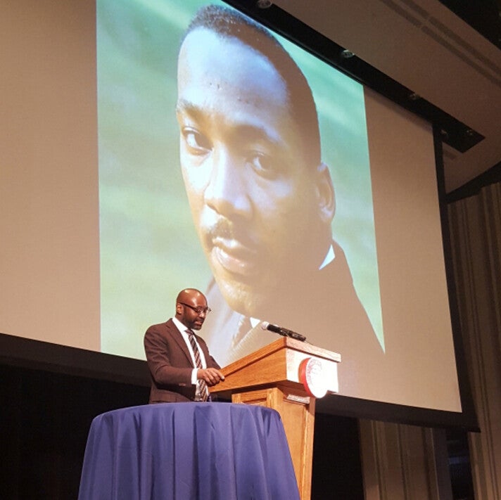 John L. Jackson speaking at podium in front of MLK photo